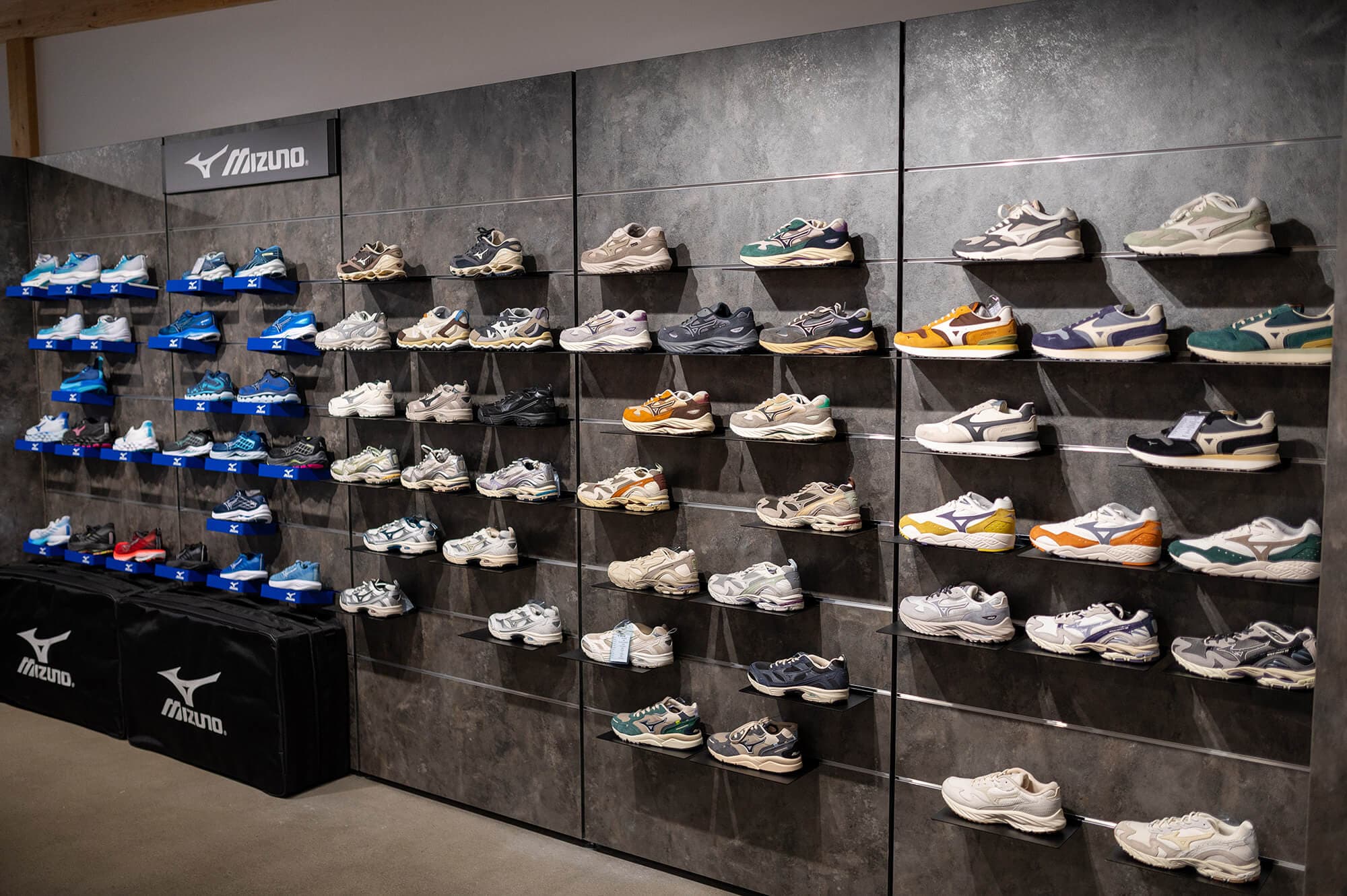 Catrade Aigles Showroom Schweiz Weiters Dekorspan. Wandanlage mit dunklerer Betonoptik, Schuhpräsentation, Lamellenwände, Schienen zur Aufhängung. Schuhe. Regalsystem